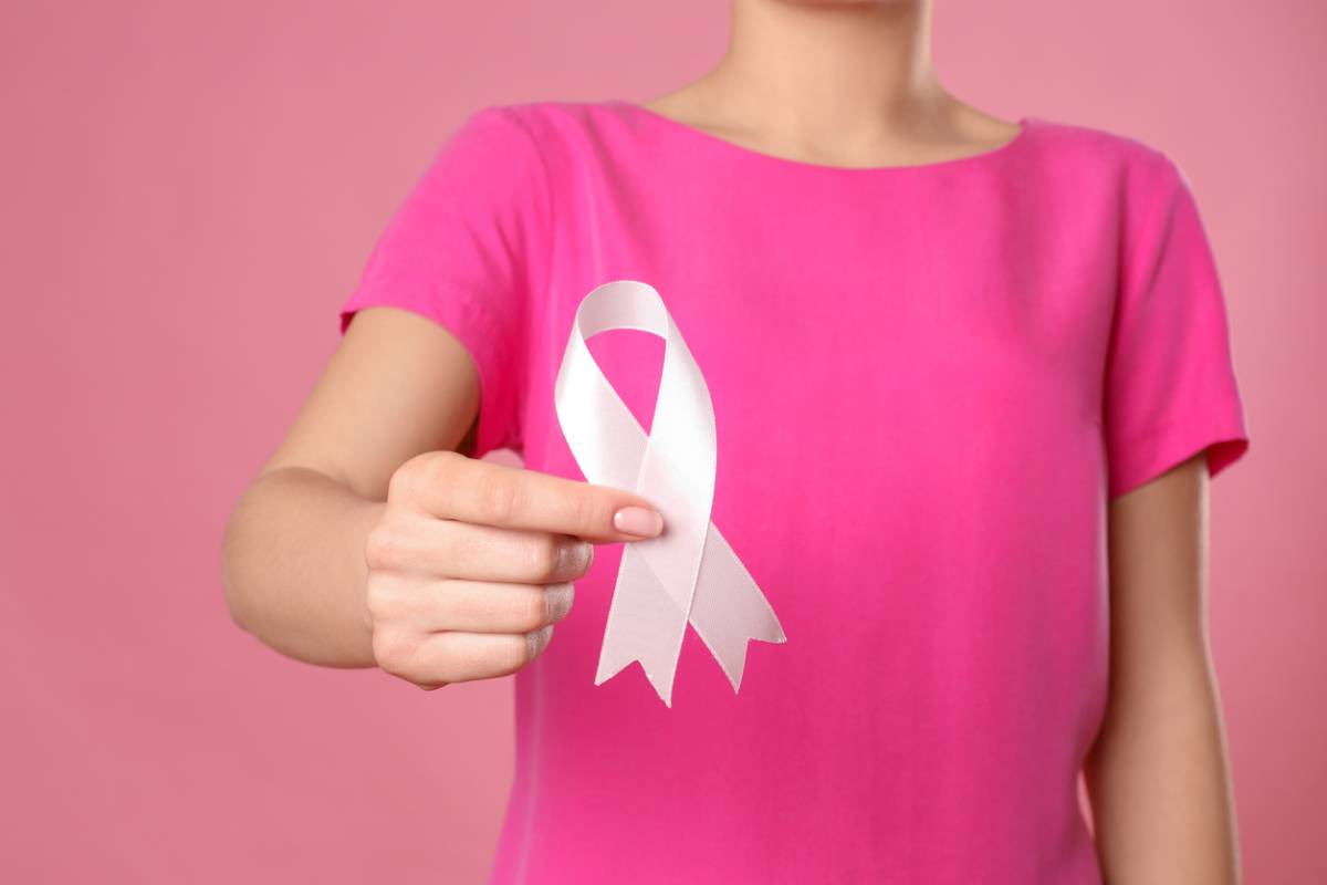 Woman holding breast cancer awareness ribbon with awareness of limitations of mammograms.